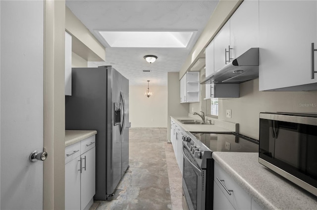 kitchen featuring a skylight, white cabinetry, sink, hanging light fixtures, and appliances with stainless steel finishes