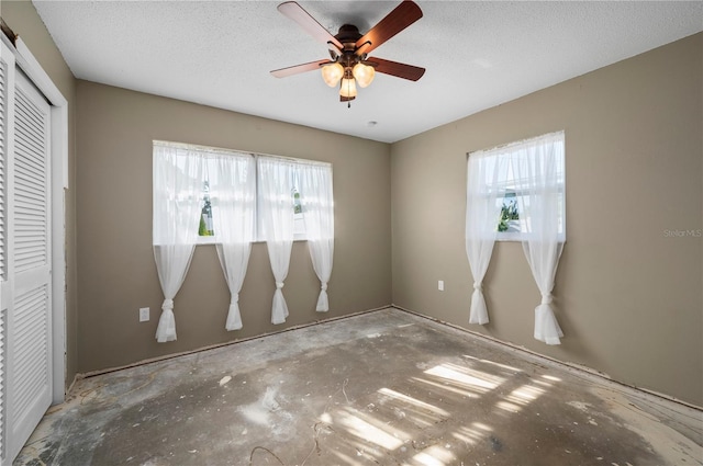 empty room featuring a textured ceiling, ceiling fan, and a healthy amount of sunlight