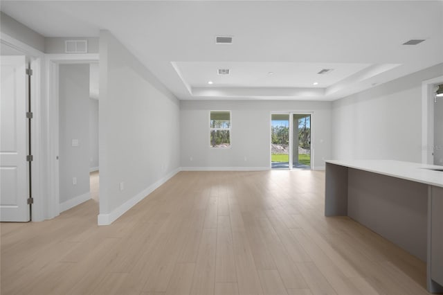 spare room featuring light wood-type flooring and a tray ceiling