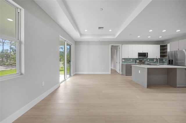 kitchen featuring backsplash, white cabinetry, light wood-type flooring, and appliances with stainless steel finishes