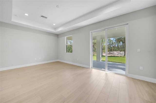 spare room featuring light hardwood / wood-style flooring and a raised ceiling