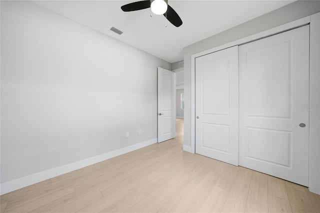 unfurnished bedroom featuring ceiling fan, a closet, and light wood-type flooring