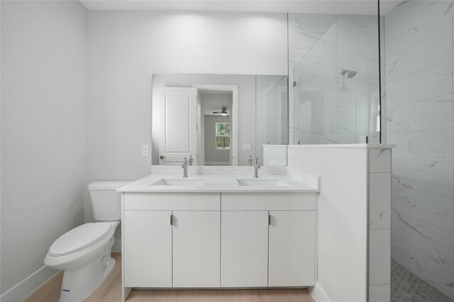 bathroom with toilet, vanity, hardwood / wood-style floors, and tiled shower