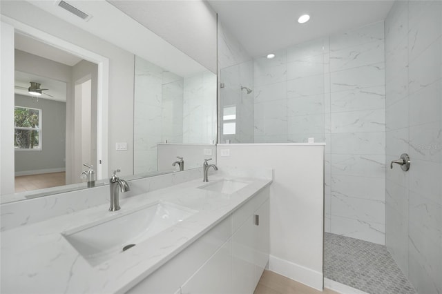 bathroom featuring wood-type flooring, ceiling fan, a tile shower, and vanity