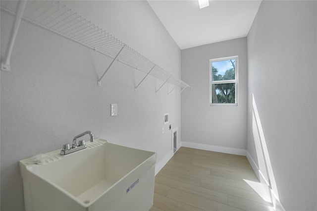 clothes washing area with hookup for a washing machine, sink, light hardwood / wood-style floors, and hookup for an electric dryer