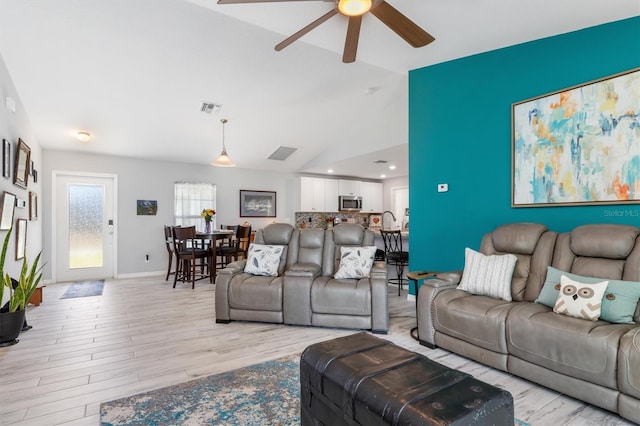 living room featuring lofted ceiling, ceiling fan, and light wood-type flooring