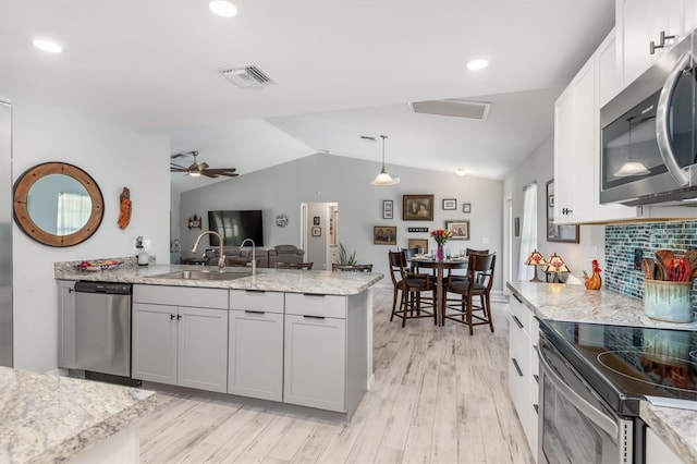 kitchen featuring pendant lighting, sink, lofted ceiling, appliances with stainless steel finishes, and light hardwood / wood-style floors