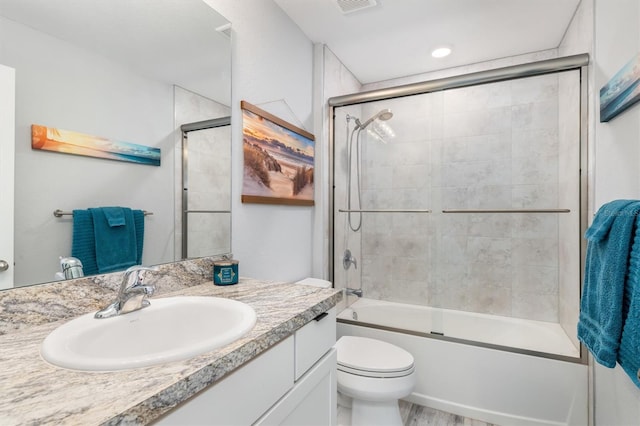 full bathroom with enclosed tub / shower combo, vanity, and toilet