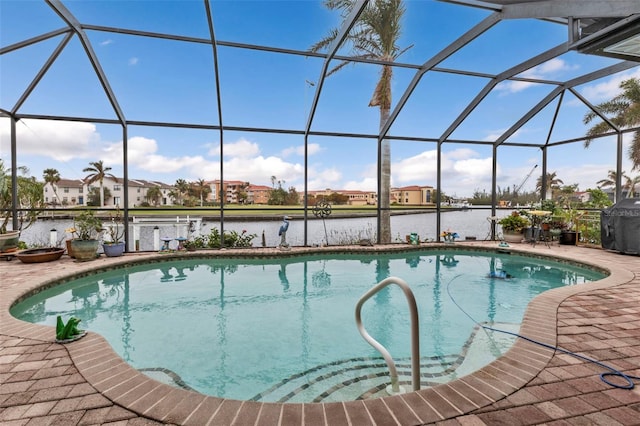 view of swimming pool with a water view, glass enclosure, and a patio area