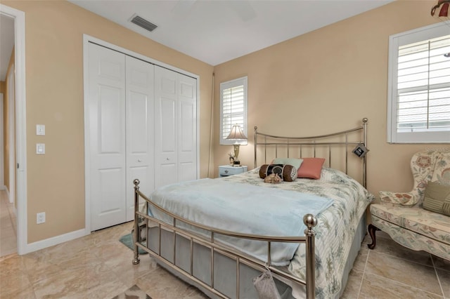 bedroom with light tile patterned flooring, ceiling fan, and a closet