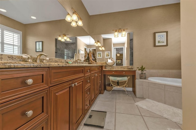 bathroom with a relaxing tiled tub, vanity, and tile patterned floors