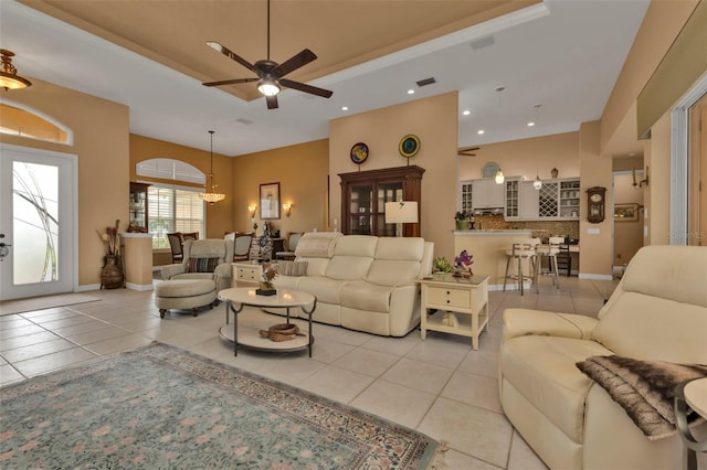 tiled living room with ceiling fan and a tray ceiling