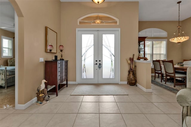 foyer entrance with light tile patterned floors, an inviting chandelier, and french doors