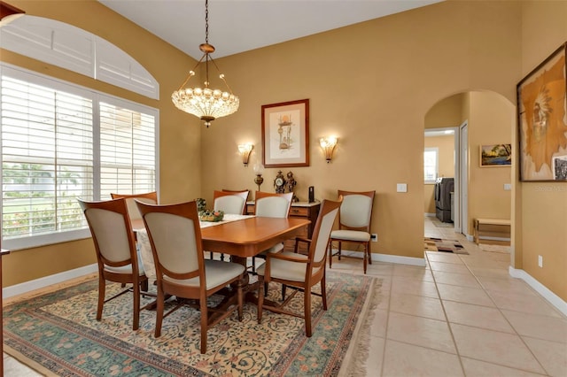 tiled dining room featuring washing machine and dryer and a chandelier