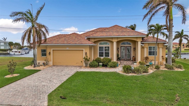 mediterranean / spanish house featuring a water view, a garage, and a front lawn