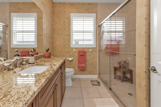 bathroom with a shower with door, vanity, tile patterned floors, and toilet