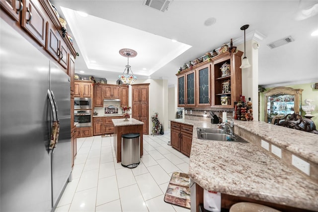 kitchen featuring built in appliances, pendant lighting, sink, a breakfast bar, and a center island