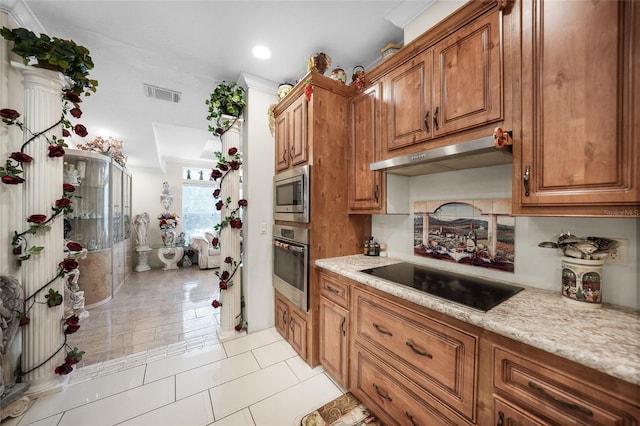 kitchen with light stone countertops, light tile patterned floors, appliances with stainless steel finishes, and ornamental molding