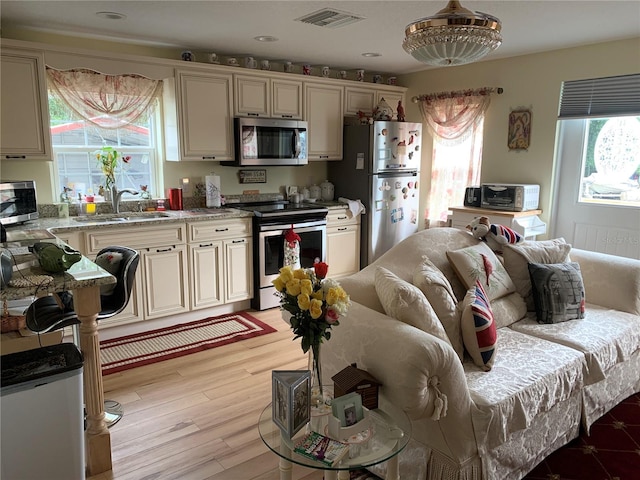 kitchen featuring stainless steel appliances, light wood-type flooring, and cream cabinets