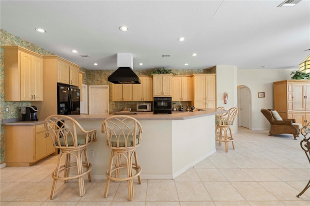 kitchen featuring light brown cabinets, black appliances, island range hood, and a breakfast bar