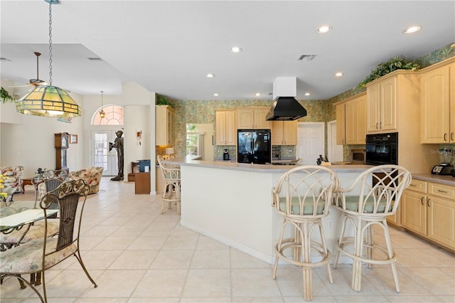 kitchen featuring black appliances, light brown cabinetry, hanging light fixtures, and a center island