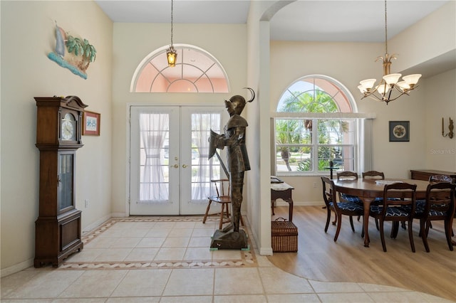 entryway with light hardwood / wood-style floors, an inviting chandelier, and french doors