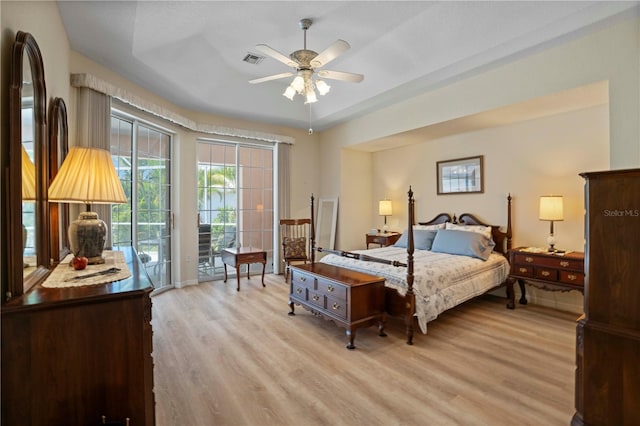 bedroom with ceiling fan, a raised ceiling, light wood-type flooring, and access to outside