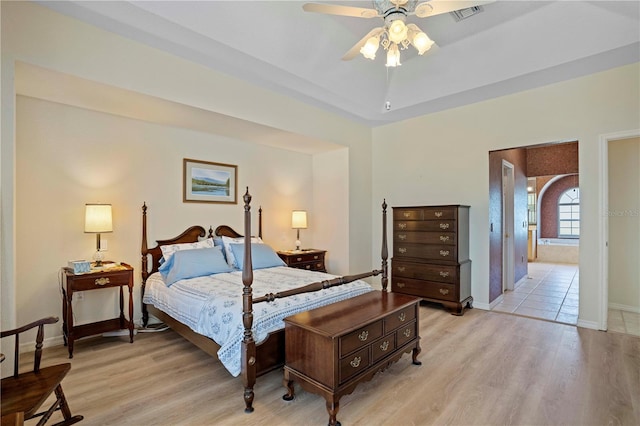 bedroom with light hardwood / wood-style floors, ceiling fan, and connected bathroom