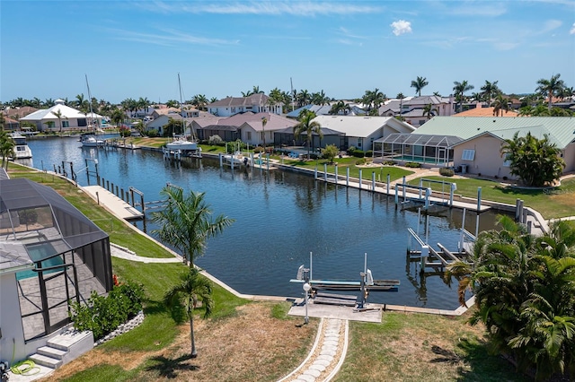 view of dock with a lanai, a water view, and a lawn