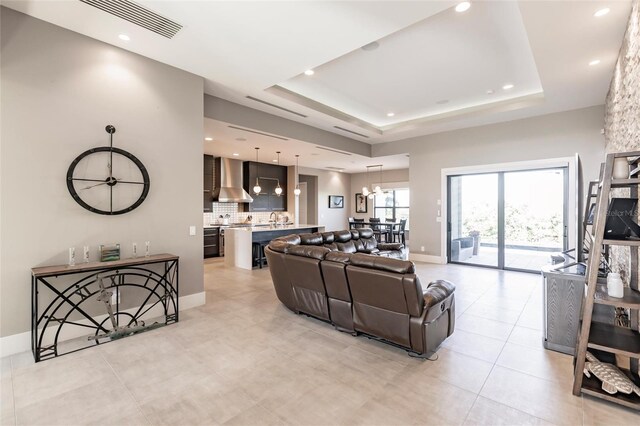 living room with a raised ceiling and sink