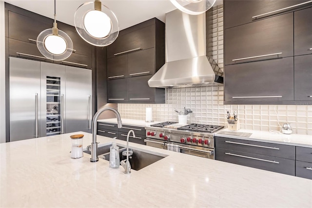 kitchen featuring pendant lighting, sink, wall chimney exhaust hood, tasteful backsplash, and premium appliances