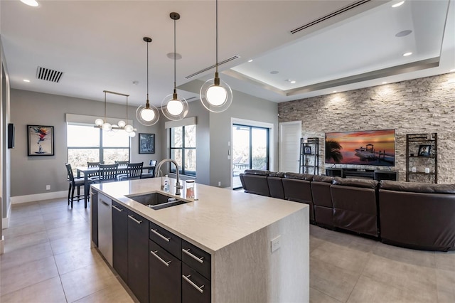 kitchen featuring decorative light fixtures, sink, a wealth of natural light, and an island with sink