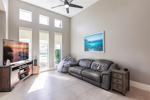 tiled living room featuring plenty of natural light, ceiling fan, and a towering ceiling