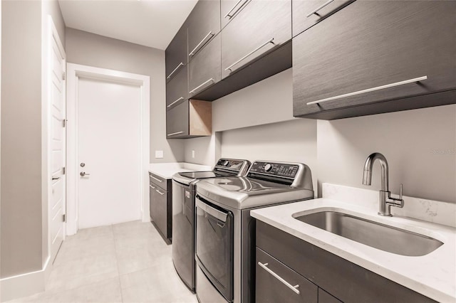 laundry area with washing machine and clothes dryer, light tile patterned flooring, cabinets, and sink