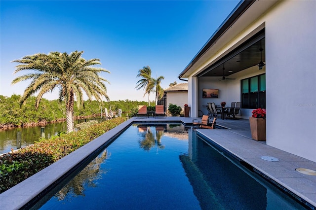 view of swimming pool with a patio, a water view, and ceiling fan