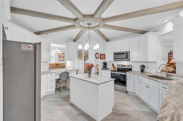 kitchen with appliances with stainless steel finishes, backsplash, sink, white cabinets, and a kitchen island