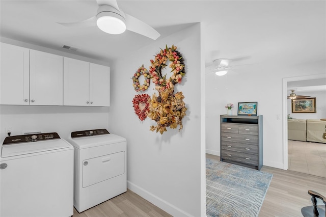 laundry area featuring washer and clothes dryer, cabinets, and light hardwood / wood-style flooring