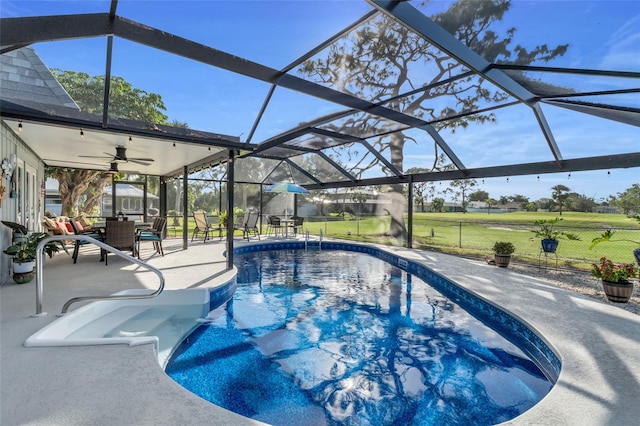 view of pool featuring a yard, a patio, glass enclosure, and ceiling fan