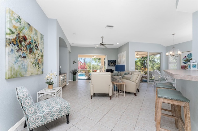 tiled living room with ceiling fan with notable chandelier