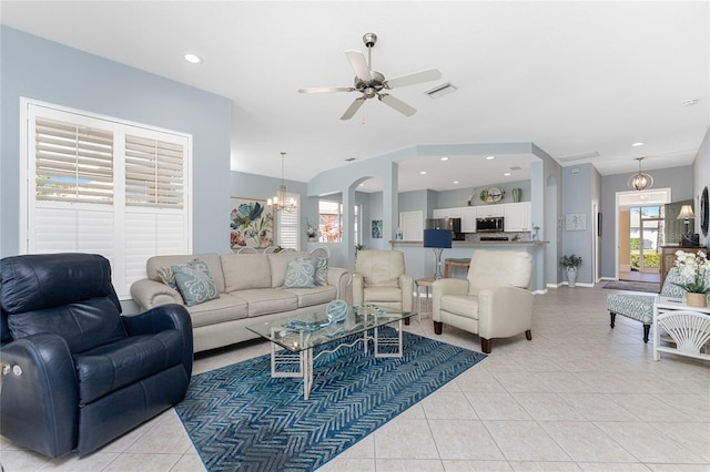 tiled living room with ceiling fan with notable chandelier