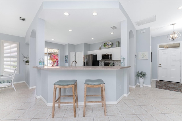 kitchen with white cabinets, a breakfast bar, kitchen peninsula, and stainless steel appliances