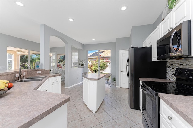 kitchen featuring sink, a center island, decorative backsplash, white cabinets, and appliances with stainless steel finishes