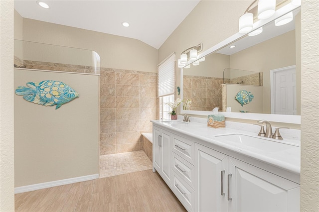 bathroom featuring a tile shower, hardwood / wood-style floors, vanity, and lofted ceiling