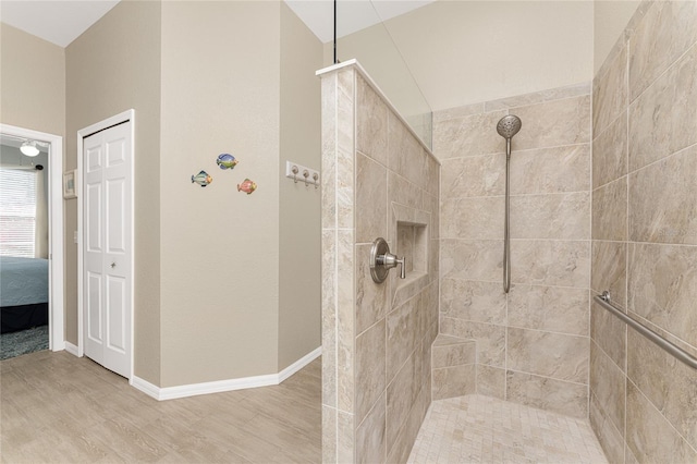 bathroom with hardwood / wood-style flooring and a tile shower