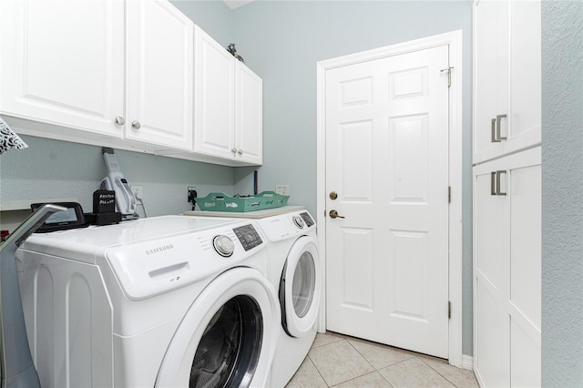 laundry room with washer and clothes dryer, light tile patterned floors, and cabinets