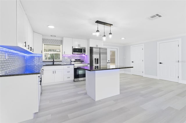 kitchen featuring white cabinets, appliances with stainless steel finishes, pendant lighting, and a center island