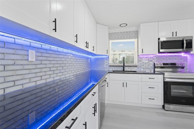 kitchen with white cabinetry, sink, backsplash, and stainless steel appliances