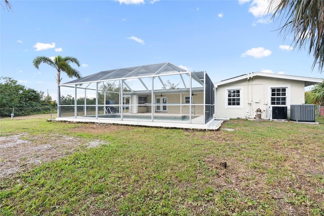 back of property with central air condition unit, a yard, and a lanai