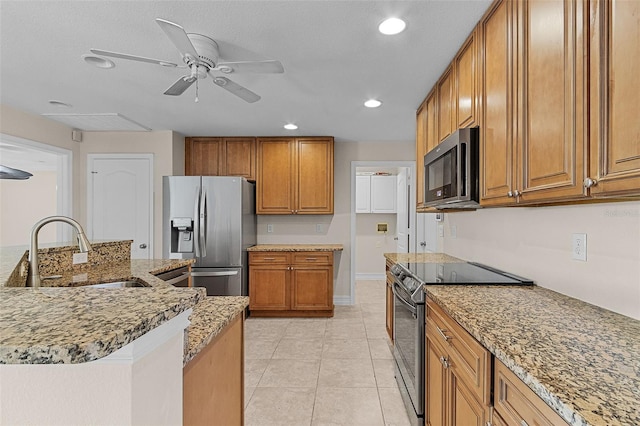 kitchen with light stone countertops, appliances with stainless steel finishes, ceiling fan, sink, and light tile patterned floors