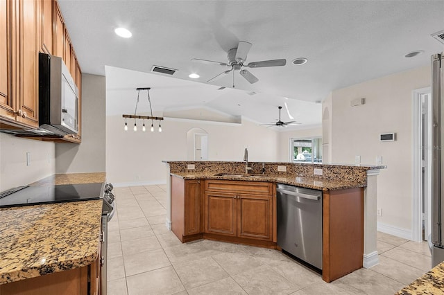 kitchen featuring stainless steel appliances, vaulted ceiling, sink, decorative light fixtures, and a center island with sink